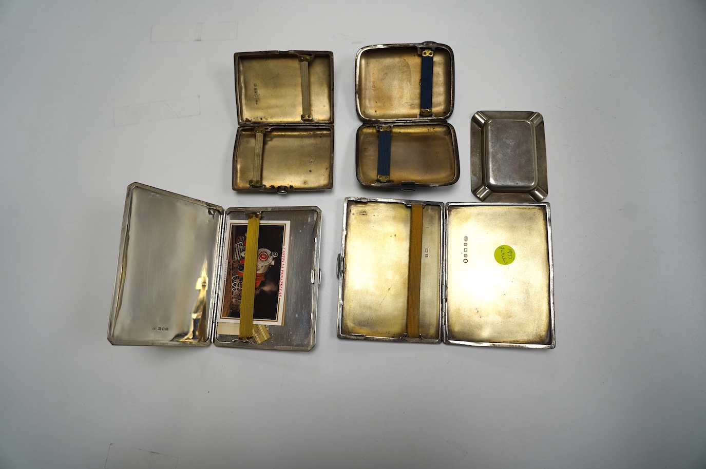 A George VI engine turned silver cigarette case, with yellow metal band, London, 1938, 11.4cm, four other silver cigarette cases and a silver ashtray, gross weight 16.8oz. Condition - poor to fair